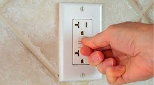 Hand resetting a GFCI electrical outlet.
