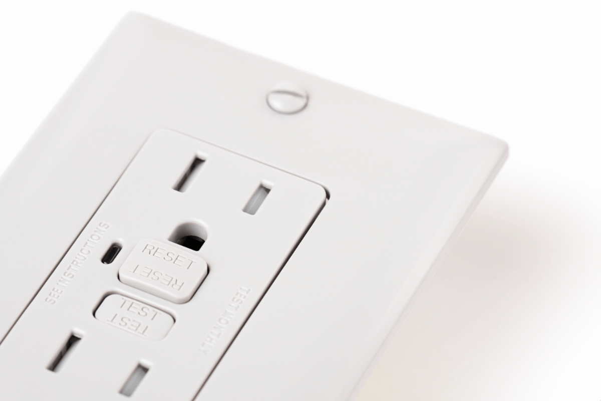 Close-up view of a white GFCI outlet with visible test and reset buttons, showing proper GFCI outlet installation.