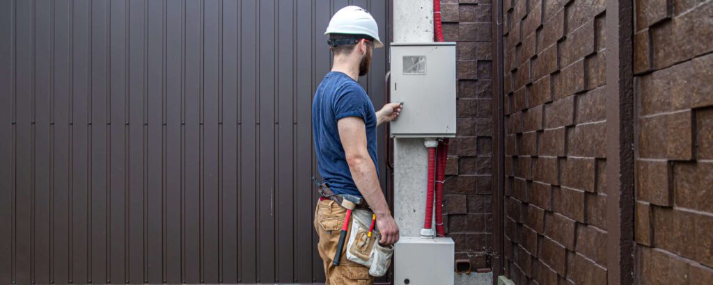 Electrician inspecting an outdoor electrical panel to install a whole house surge protector.