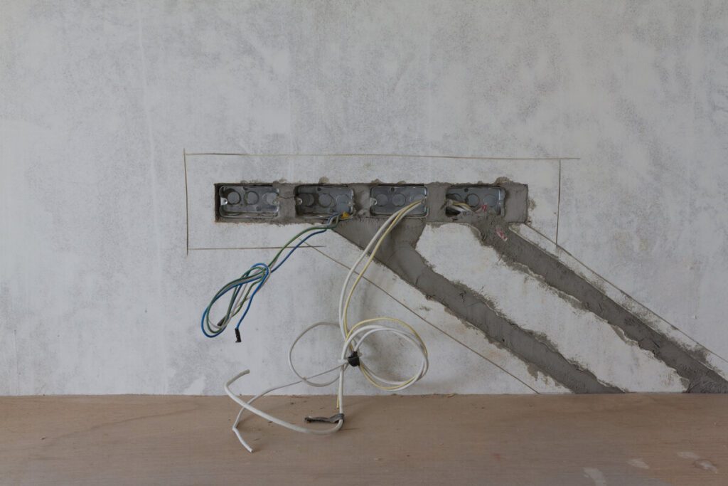 Electrical wiring repair in progress with exposed cables and wall-mounted outlet boxes.