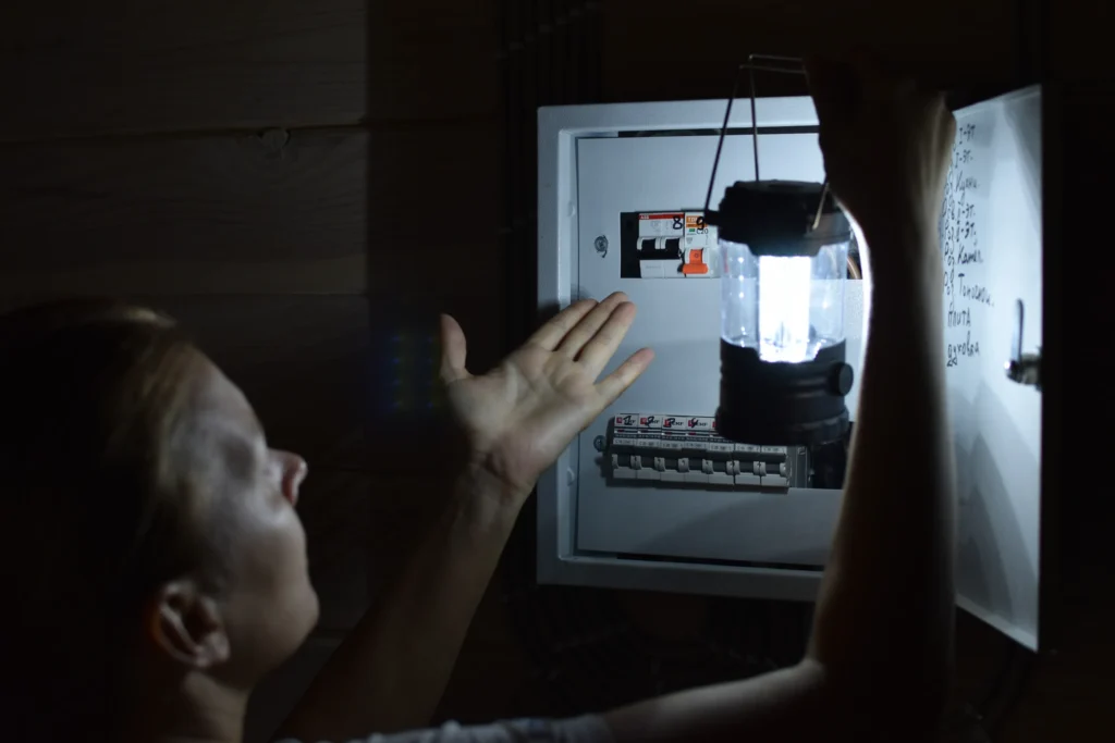 Homeowner checking an electrical panel with a lantern during a Texas power outage.