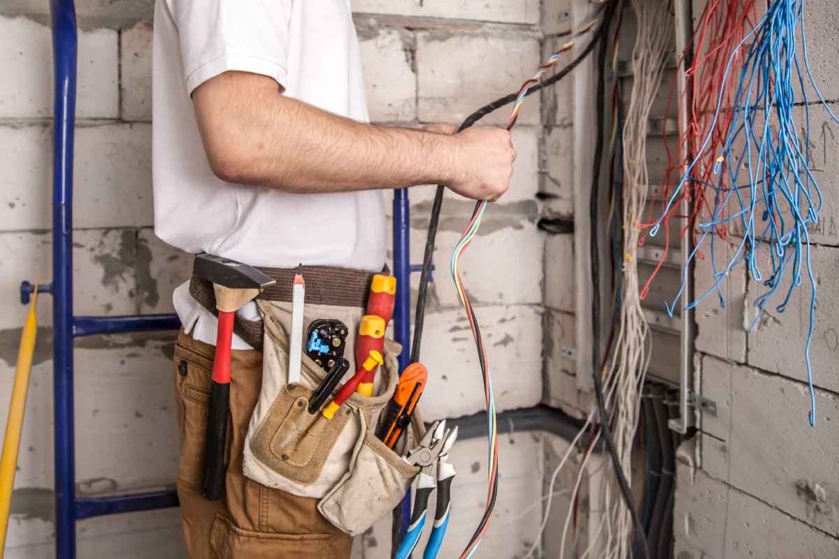 A professional electrician handling bundled wires during service work for Generator Maintenance in North Texas, ensuring safe and reliable power systems.