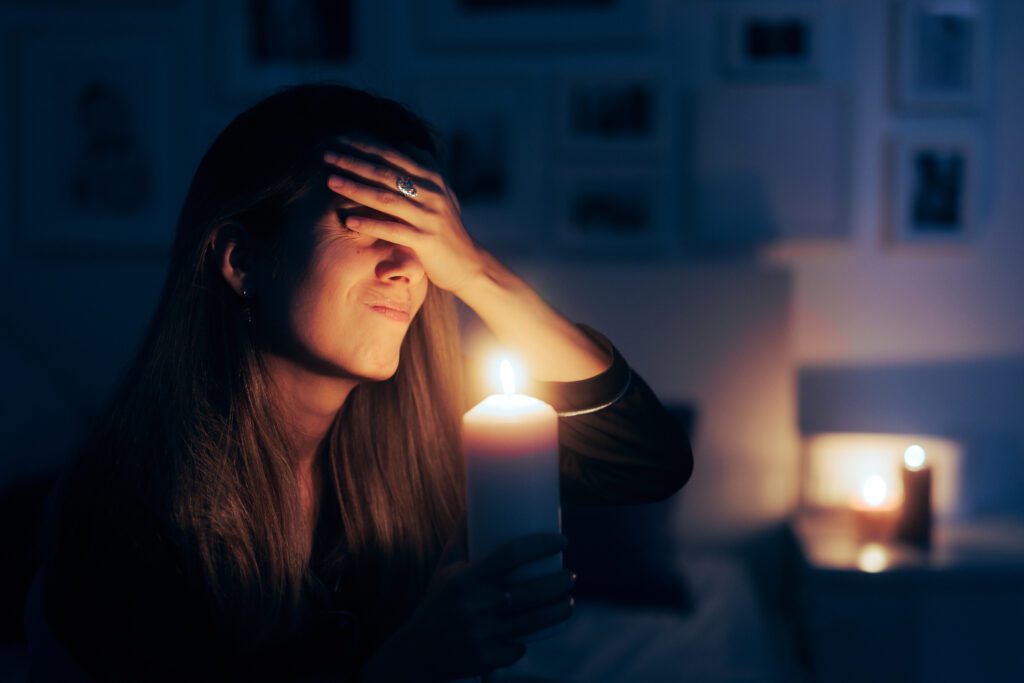 Woman holding a candle during a blackout caused by January Storms in Rockwall, showing concern over a power outage.