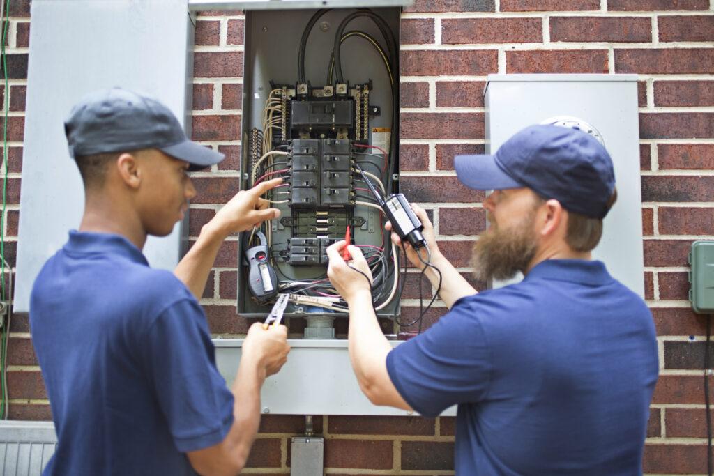 Two licensed electricians test a breaker box after electrical rewiring in Garland.