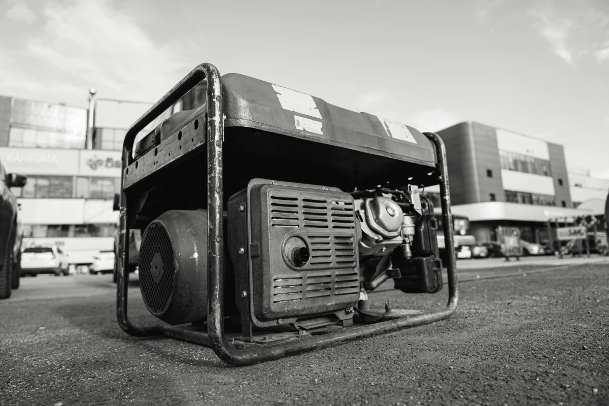 Portable generator with a metal frame and exposed engine components placed on the ground.